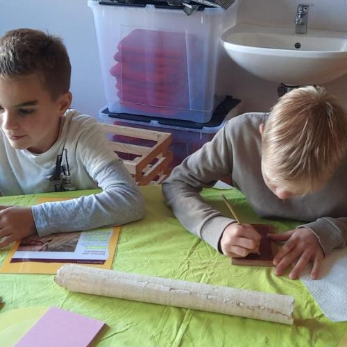 Kinder schreiben auf Papyrus