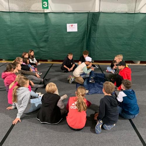 Kinder sitzen im Kreis am Boden