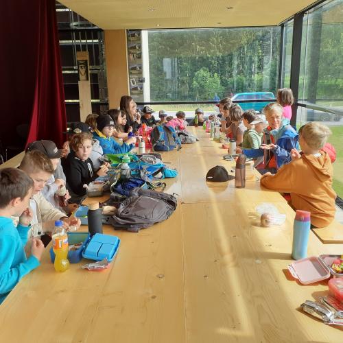 Kinder jausnen an großem Tisch