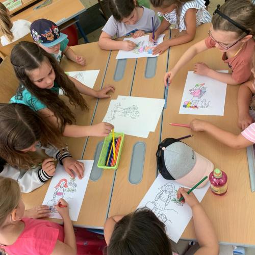 Kinder sitzen um einen Tisch und malen