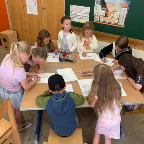 Kinder sitzen um einen Tisch und malen