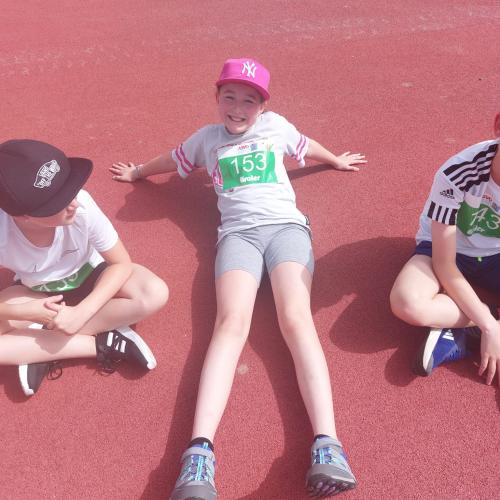 Kinder sitzen auf Sportplatz