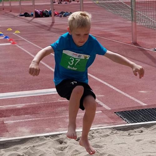 Kind springt in Sandkasten