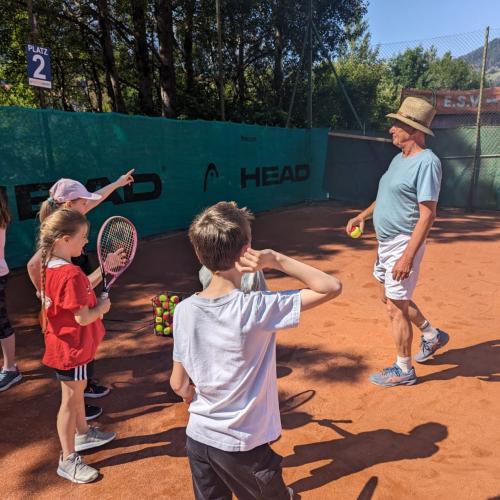 Kinder und Mann auf Tennisplatz