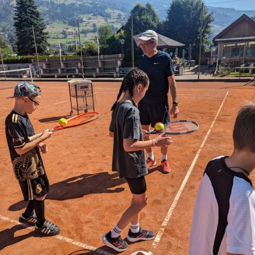 Kinder und Mann auf Tennisplatz