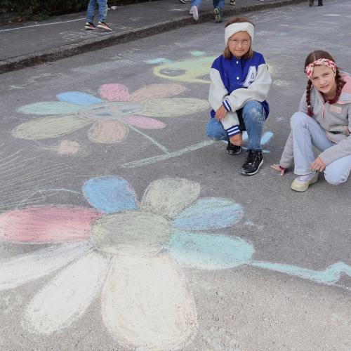 Mädchen malen große Blumen auf Straße
