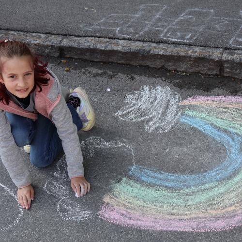 Mädchen male Regenbogen auf Straße