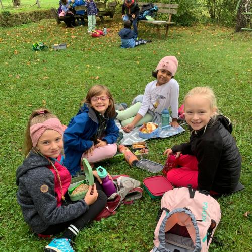 Kinder sitzen im Gras und jausnen