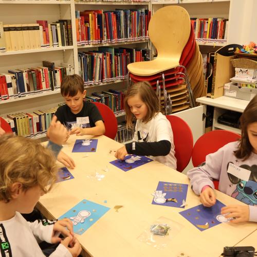 Kinder sitzen an Tisch und basteln