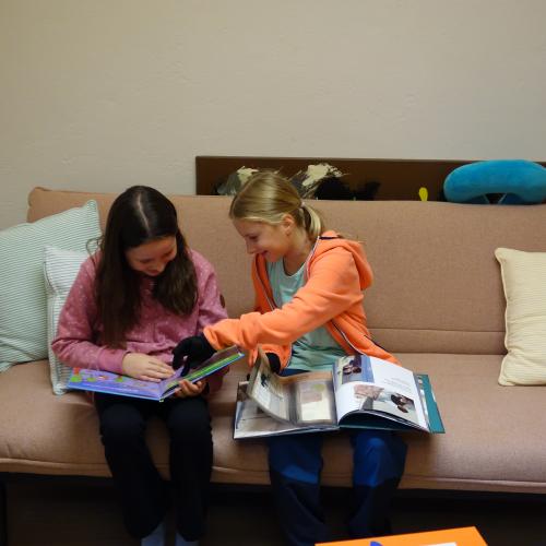 zwei Mädchen auf Sofa mit Bilderbüchern