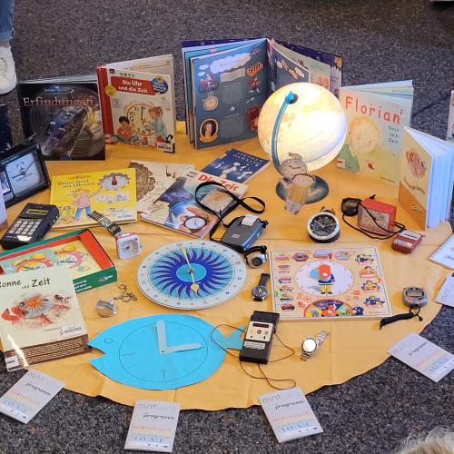 viele Bücher und Uhren auf gelbem Tuch