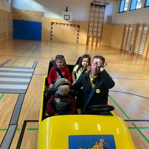 Kinder und Mann in kleinem gelben Auto