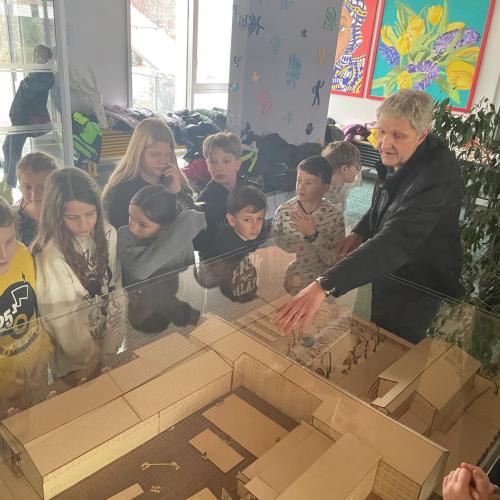 Kinder, ein Lehrer und ein Modell einer Schule