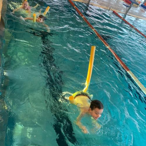 Kinder in Schwimmbecken mit Schwimmnudeln