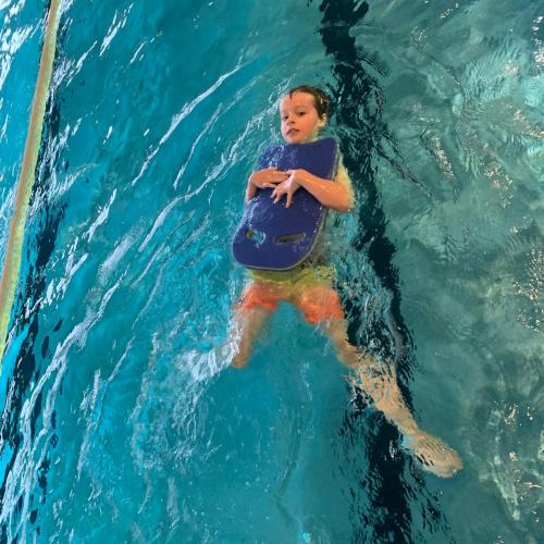 Kind mit Schwimmbrett beim Rückenschwimmen