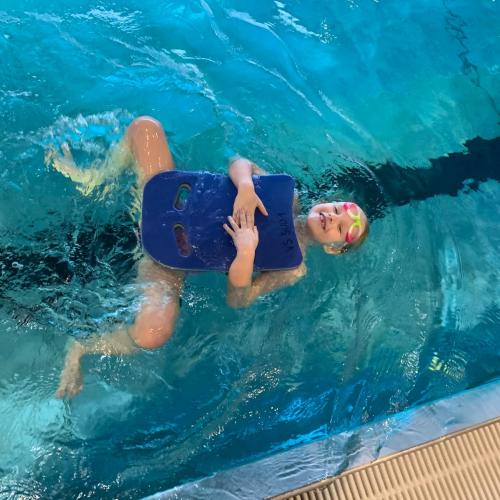 Kind mit Schwimmbrett beim Rückenschwimmen