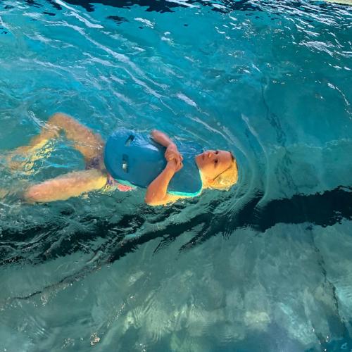 Kind mit Schwimmbrett beim Rückenschwimmen