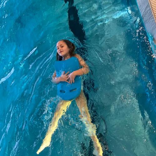 Kind mit Schwimmbrett beim Rückenschwimmen