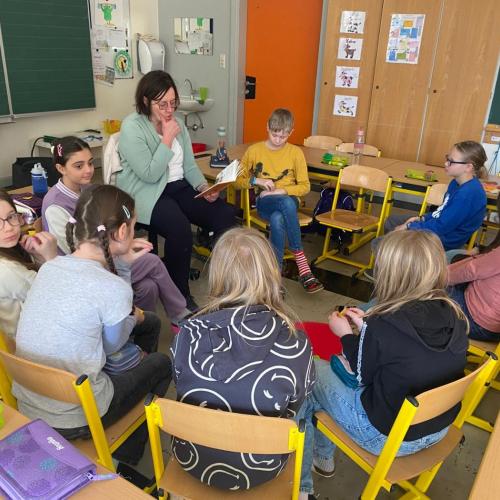 Frau und Kinder sitzen im Kreis