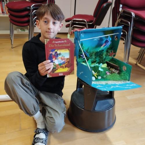 Bub zeigt Buch und Bastelarbeit