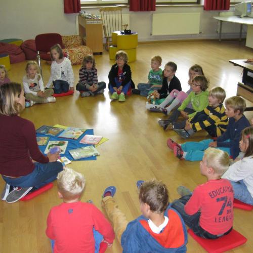 Kinder sitzen am Boden im Kreis