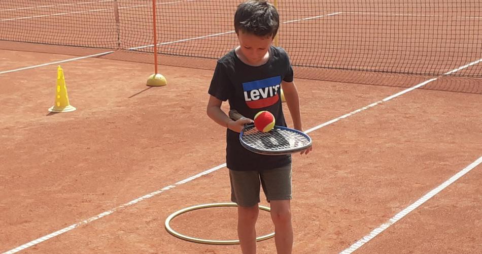 Kind balanciert Tennisball mit Tennisschläger